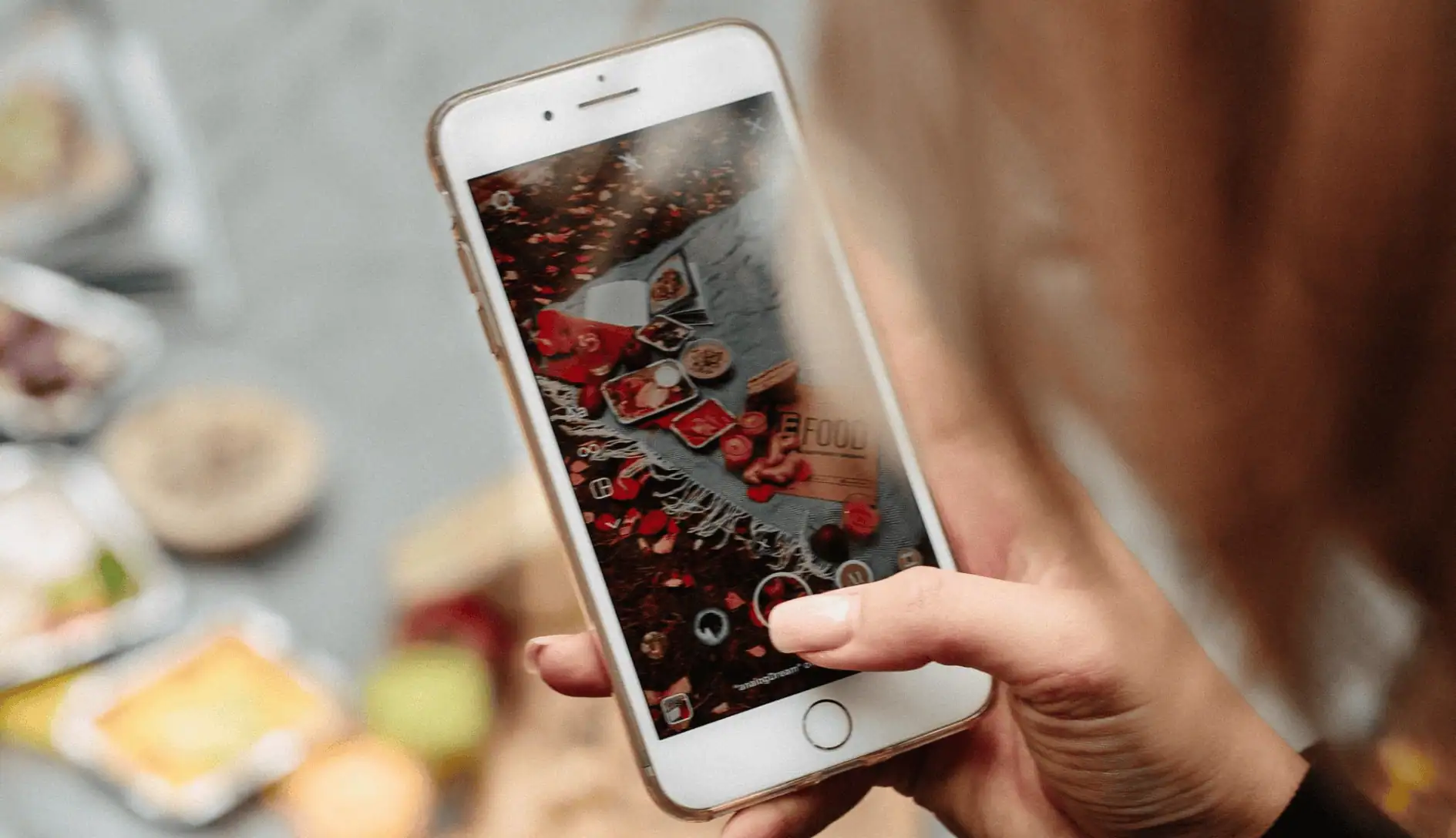 A woman taking a photo of a spread of food using an iPhone