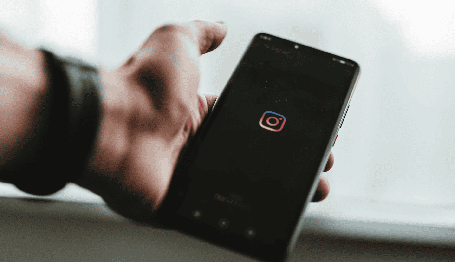 Person holding an iPhone with a black screen and the Instagram logo in the centre.